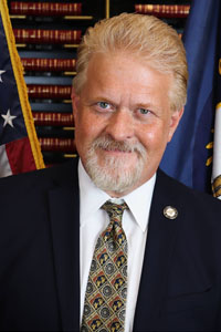 Portrait of Edward West in front of the American and Kentucky flags.